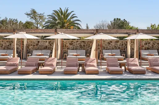 Outdoor pool with cushioned pool chairs and white umbrellas