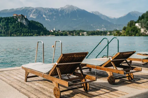 Two wooden lounge chairs on a deck overlooking the water