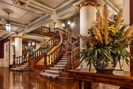 Lobby with large, wooden staircase with vases 