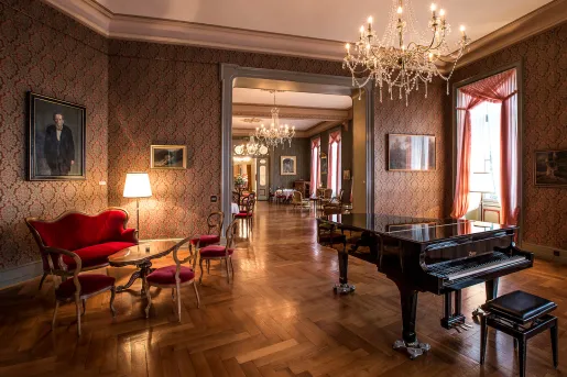 Indoor lobby with red, cushioned chairs and a piano on the right