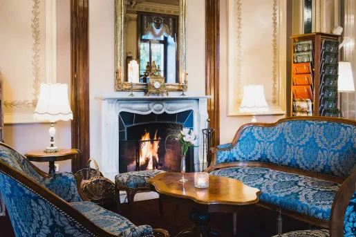 Indoor lounge with blue, cushioned chairs in front of a fireplace