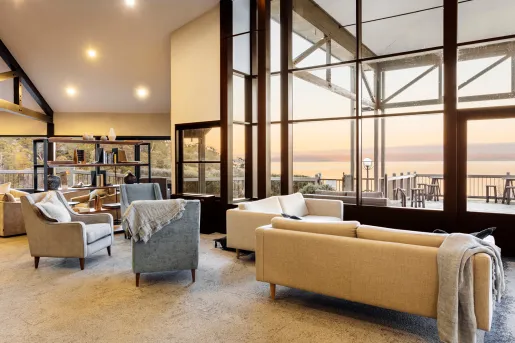 couches and chairs in a room with floor to ceiling windows