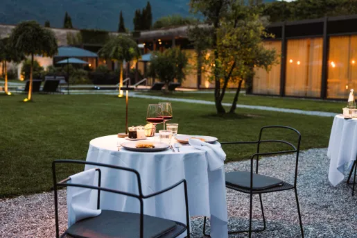 Outdoor dining table with a white cloth and two plates of food and two glasses of wine