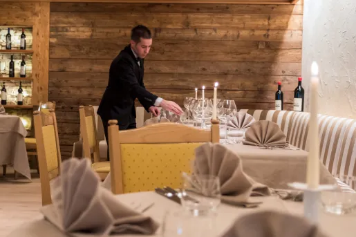 Man in a suit organizing a dining table at a restaurant