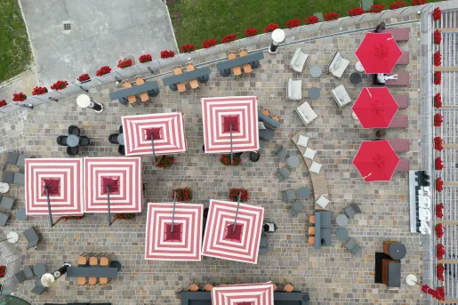 Top view of square red and pink umbrellas in a stone-floored courtyward