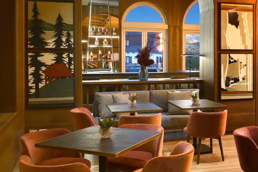 Indoor bar and lounge with square tables and cushioned chairs