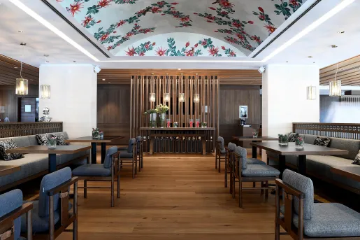 Indoor dining area with square tables and plants on each table