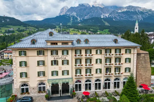 Exterior view of 4-story hotel building with mountains in the distance