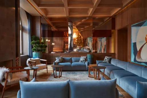 Indoor lounge with blue, cushioned seats and paintings on the wall