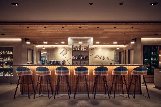Indoor bar and lounge, with an illuminated bar counter and brown bar stools