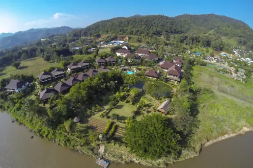 Sky view of tan buildings with brown roofs next to a lake and open valley