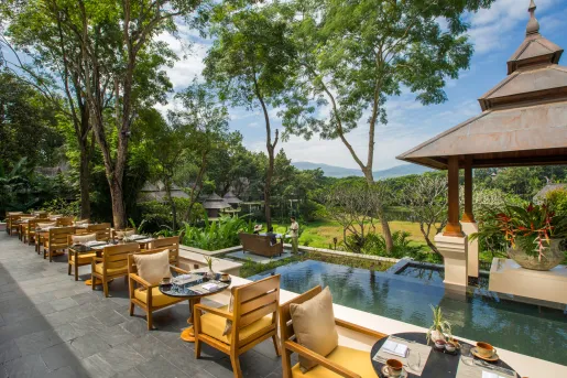 tables and chairs next to a pool