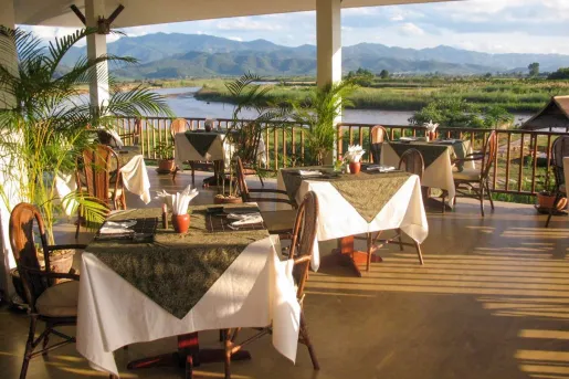 Outdoor patio dining area with a view of an open valley and lake in the distance
