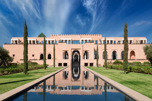Exterior, wide view of rectangular, castle-like building with a long fountains and tall trees