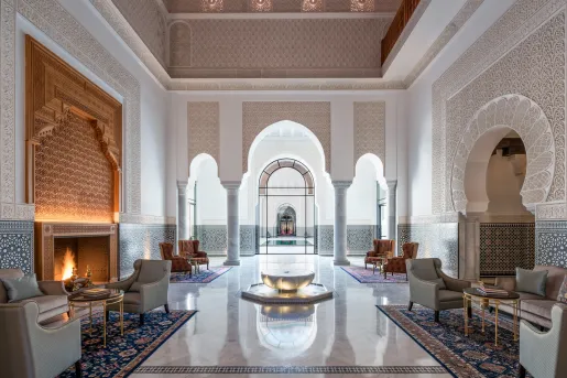 Hotel lobby with marble flooring and large stone pillars under an archway