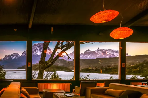 Indoor lounge with orange lights and wide windows, looking out towards mountains