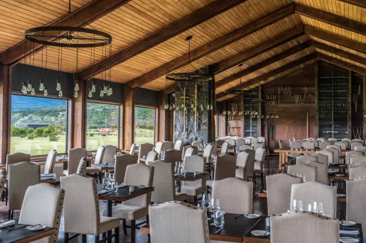 Dining hall filled with tables and white cushioned chairs