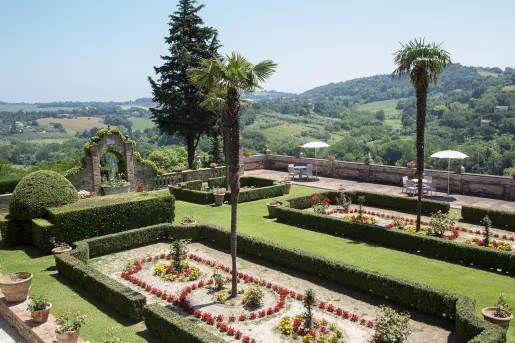 Outdoor garden with trimmed bushes, and stone barricades and statues