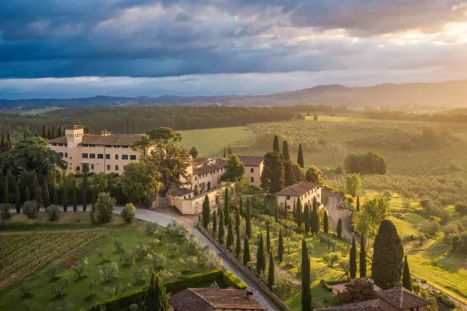 Exterior view of tan and brown buildings, surrounded by large crop fields and mountains