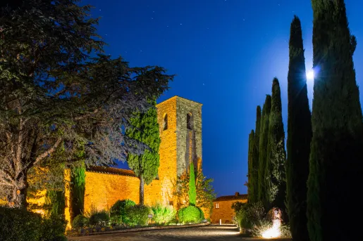 Nighttime view of stone building and trees illuminated by lights
