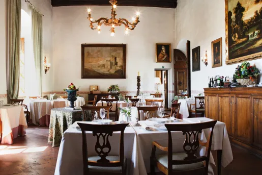 Indoor dining area with white tablecloths and a candle chandelier on the ceiling