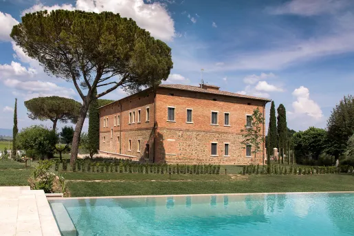 Brick building with a large tree on the left and an outdoor pool in front