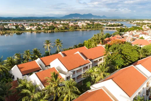 Rows of white buildings with orange roofs, looking out towards a small lake