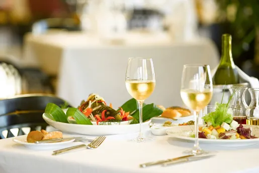 Dining table with two plates of food, and two half empty glasses of white wine