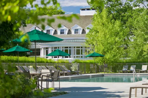 Exterior view of white building with an outdoor pool, surrounded by green umbrellas