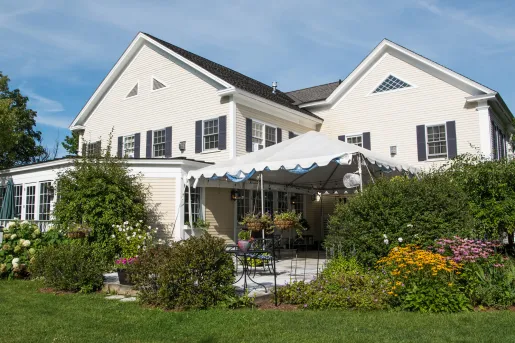 Exterior view of a white building with a grass area with bushes in front