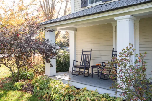 Black rocking chairs in front of a white house