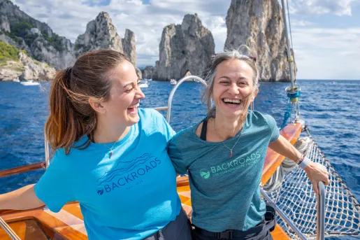 Two women on a boat, smiling while holding onto railings