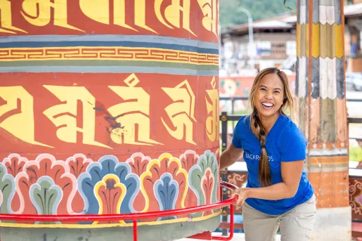 Woman smiling while holding a giant bell in a temple