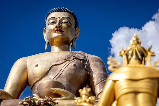 Large, bronze statue with blue sky and clouds in the background