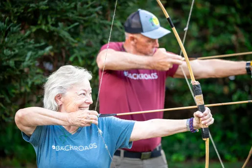 Man and woman smiling with holding a bow and arrow