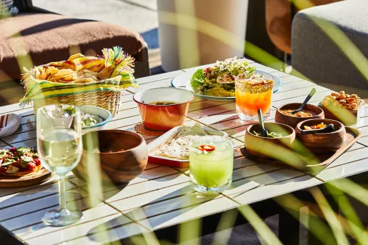 Outdoor table full of food and alcoholic drinks