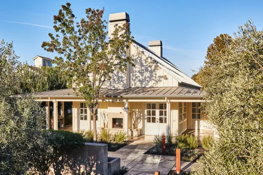White building with a porch, surrounded by tall trees