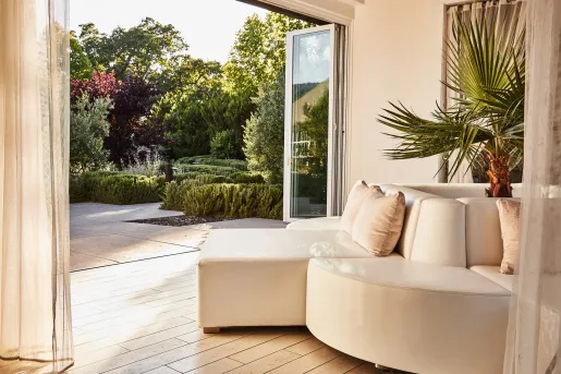 White cushioned couch with open doors leading to a garden