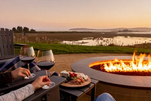 Outdoor fire pit with two glasses of wine and a charcuterie board 