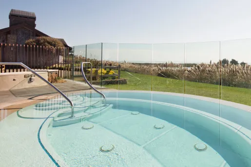 Outdoor pool surrounded by glass walls, looking out to the ocean