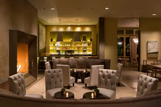 Indoor bar with tall cushioned chairs and a fireplace on the left