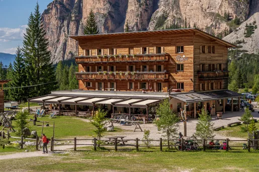 Exterior view of cabin building with a large mountain in the background, surrounded by pine trees