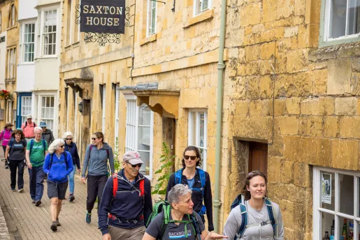 Group of people walking on a stone pathway next to brick buildings
