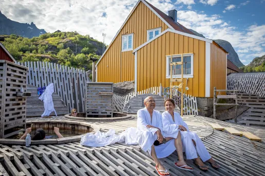 Man and woman in bath robes sitting outside next to hot tub baths