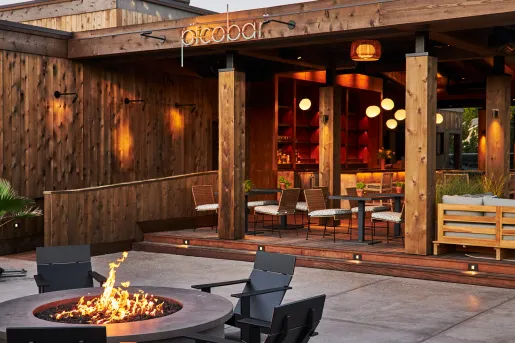 Outdoor bar and lounge with a fire pit and tables with chairs