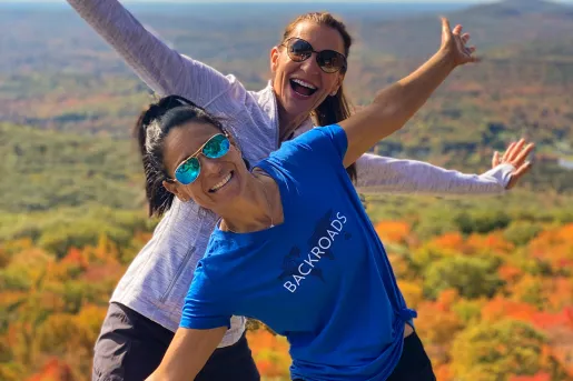 Two women with arms open wide and smiling