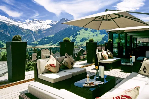 Outdoor patio with green and white furniture, with large mountains in the distance