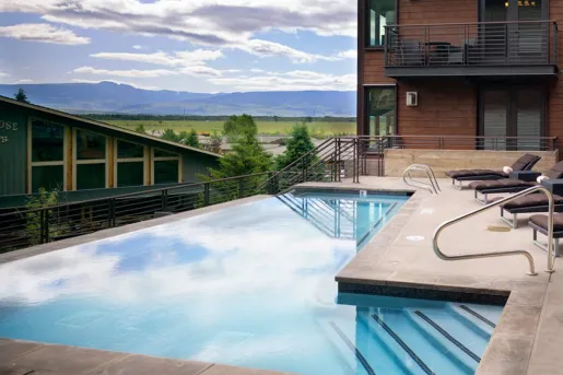 Outdoor infinity pool with a red brick hotel building on the right