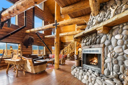 Wooden cabin lobby with giant wooden pillars and a stone fireplace on the right