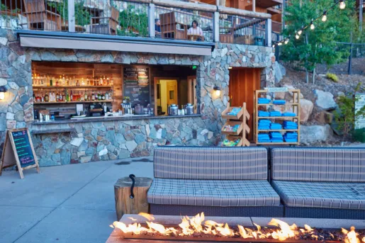 Outdoor bar area with a stone wall and a sofa in front of a stone fire pit